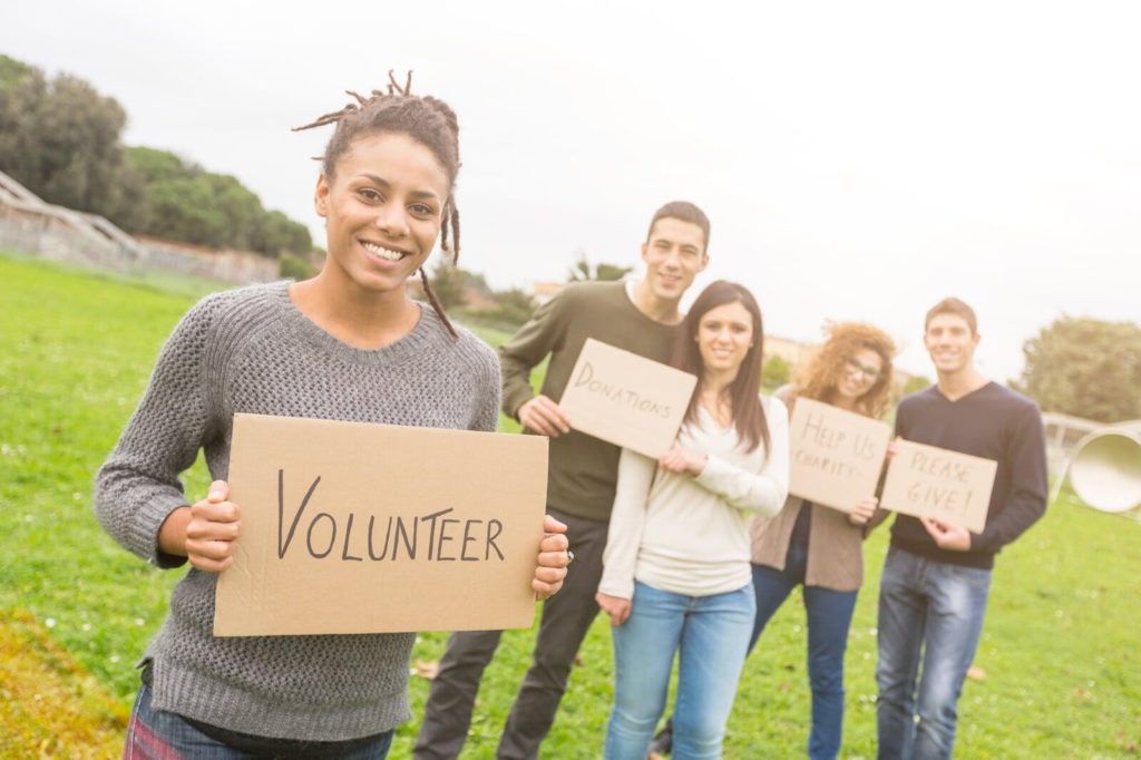 Making parents feel welcome increases the chance they'll volunteer. Picture of adults holding a sign that says, 'Volunteer'.